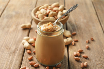 Spoon and glass jar with creamy peanut butter on kitchen table