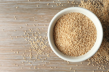 White quinoa in ceramic bowl on wooden background