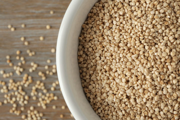 White quinoa in ceramic bowl on wooden background