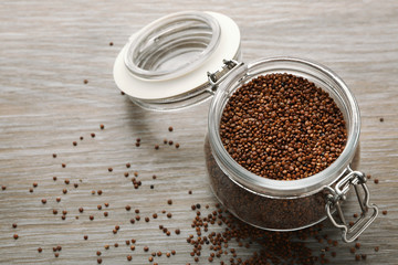 Red quinoa in glass jar on wooden background