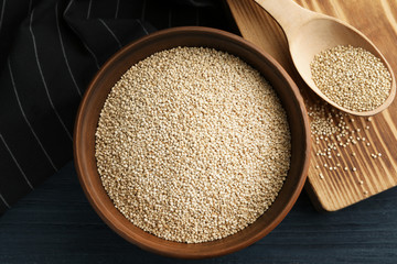 White quinoa in bowl and wooden spoon on kitchen table