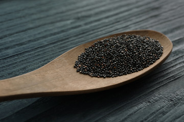 Spoon with black quinoa grains on wooden background