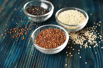 White, red and black quinoa in glass bowls on wooden background