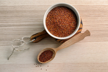 Red quinoa in wooden spoon and bowl on kitchen table