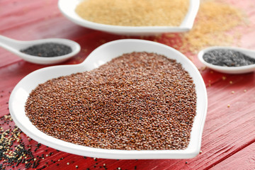 Red quinoa in heart shaped plate on wooden background