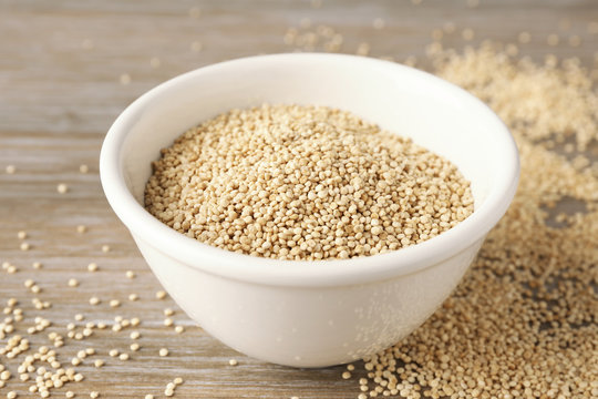 White quinoa in ceramic bowl on wooden background