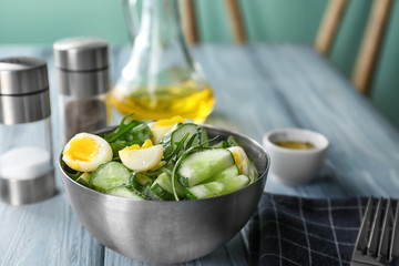 Healthy salad with cucumbers and eggs in bowl on table