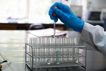 chemist dropping the clear reagent into test tube for reaction testing in chemical laboratory, with chemical equations and periodic table background.