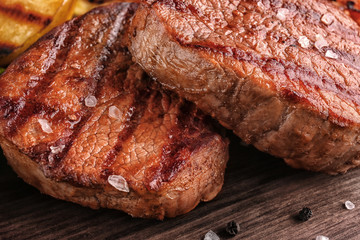 Tasty grilled steaks on table, closeup