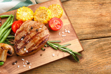 Tasty grilled steak with vegetables on table