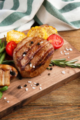 Tasty grilled steak with vegetables on table