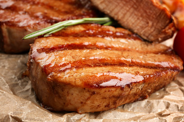 Tasty grilled steaks on parchment, closeup