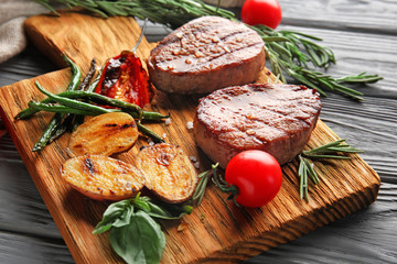 Composition with delicious steaks and vegetables on wooden table
