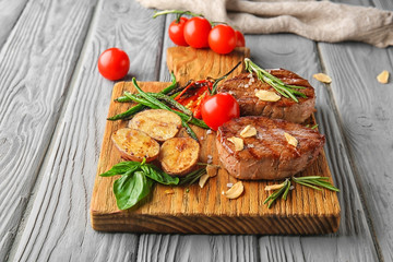 Composition with delicious steaks and vegetables on wooden table