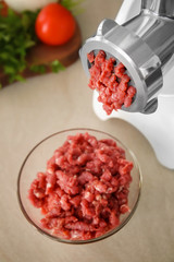 Meat grinder with fresh forcemeat on kitchen table