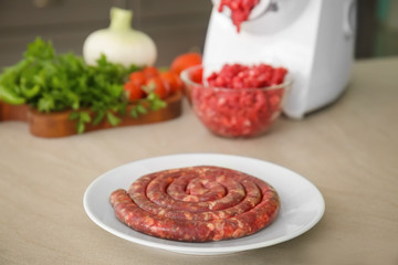 Plate with fresh forcemeat and meat grinder on kitchen table