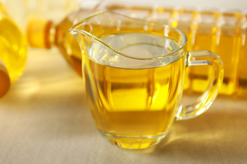 Jug with cooking oil on light background