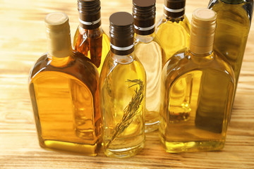 Bottles with different cooking oil on wooden background