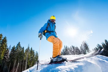 Abwaschbare Fototapete Wintersport Rearview shot of a skier enjoying skiing the slope at ski resort in the mountains on a sunny winter day copyspace seasonal activity sport sportsman hobby recreation travel concept
