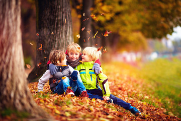 happy kids, friend having fun among fallen leaves in autumn park