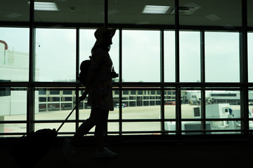 Silhouette of woman hanging camera and luggage for traveling at the airporttravel concept, people in the airport