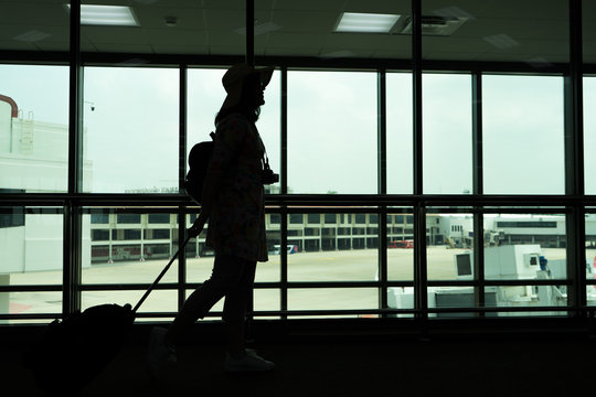 Silhouette of woman hanging camera and luggage for traveling at the airporttravel concept, people in the airport