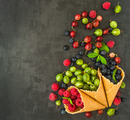 Berries. Raspberries, blackberries, blueberries in waffle cones on a wodden background. Healthy food concept.Gray stone background.Top view.