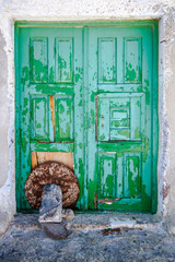 Green wooden door closed on Santorini.