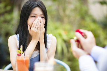 Man showing engagement ring diamond to girlfriend in restaurant. © Tom Wang