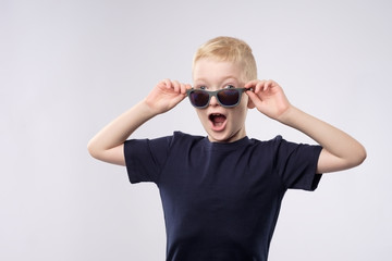 Portrait of a little caucasian boy with blond hair wearing sunglasses.