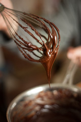 Chocolate ganache dripping from a wire whisk