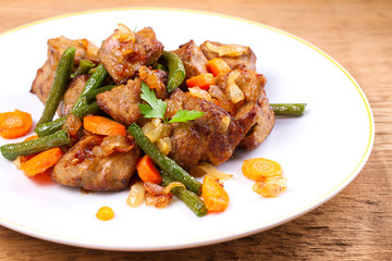 Beef liver with vegetables: carrot, onion and green beans on white plate, horizontal