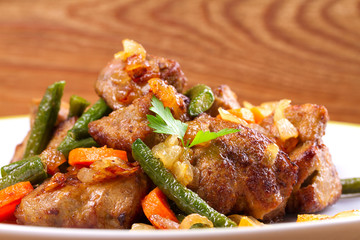 Beef liver with vegetables: carrot, onion and green beans on white plate, horizontal
