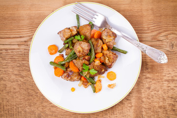 Beef liver with vegetables: carrot, onion and green beans on white plate. Top, overhead, above view, horizontal