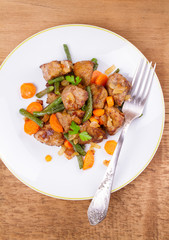 Beef liver with vegetables: carrot, onion and green beans on white plate. Top, overhead, above view, vertical