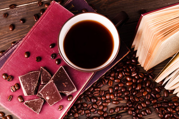 Cup of coffee stands on book with chocolate