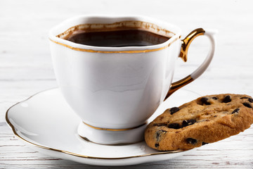 Chocolate cookie lies on the palte of white cup of coffee