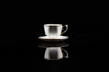 Coffee splashes in white cup on black background