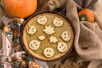 Pumpkin Pie decorated for Halloween. Fresh round bright orange homemade pumpkin pie on table.Thanksgiving background, top view.