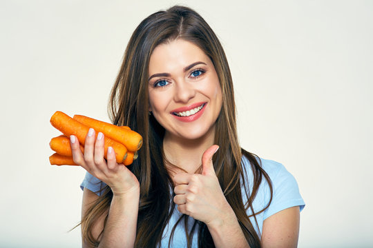 Smiling woman holding carrot giving thumb up
