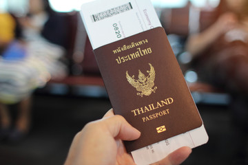 Man's hand holding Thailand passport with ticket