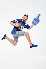 Screaming man fan in blue t-shirt jumping holding rugby ball.