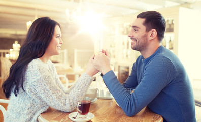 Obraz na płótnie Canvas happy couple with tea holding hands at restaurant