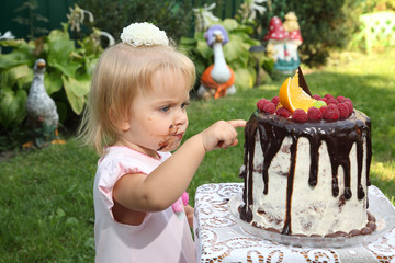 Girl birthday. A little white-haired girl of two years is trying a birthday cake. Little girl...