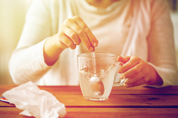 woman stirring medication in cup with spoon
