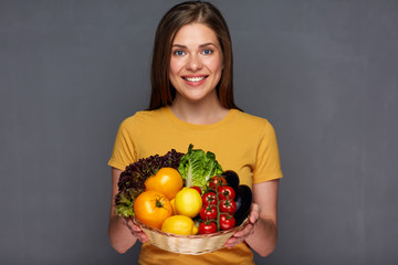 woman holding basket with summer vegetables.