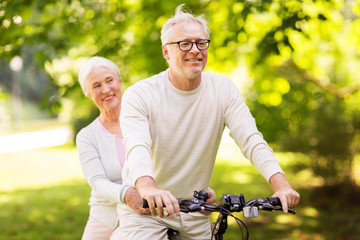 happy senior couple riding bicycle at park