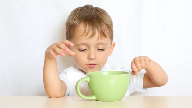 child eats food with a spoon sitting at the table