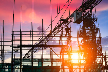 Construction site with crane and workers at sunset