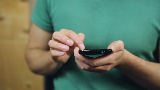 Close-up of male hands browsing necessary information on smartphone, texting